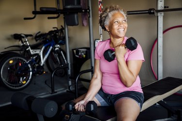 A 50-year-old person losing weight by lifting weights in her garage