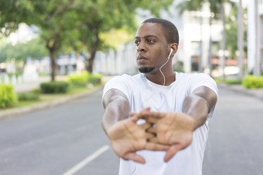 Man doing a wrist stretch after doing push-ups outside