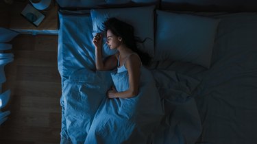 Top view of a woman sleeping in bed, to represent metabolism while sleeping